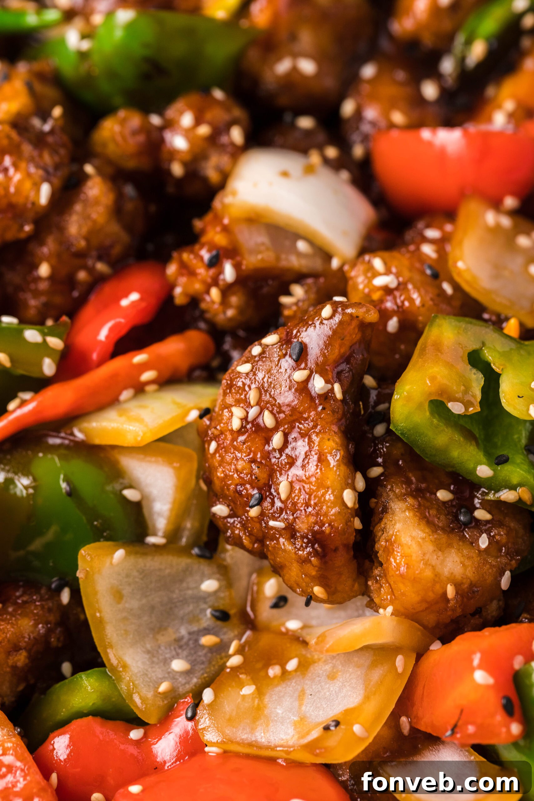 A very close-up angle of the succulent General Tso Chicken, showing off its rich sauce and garnishes.