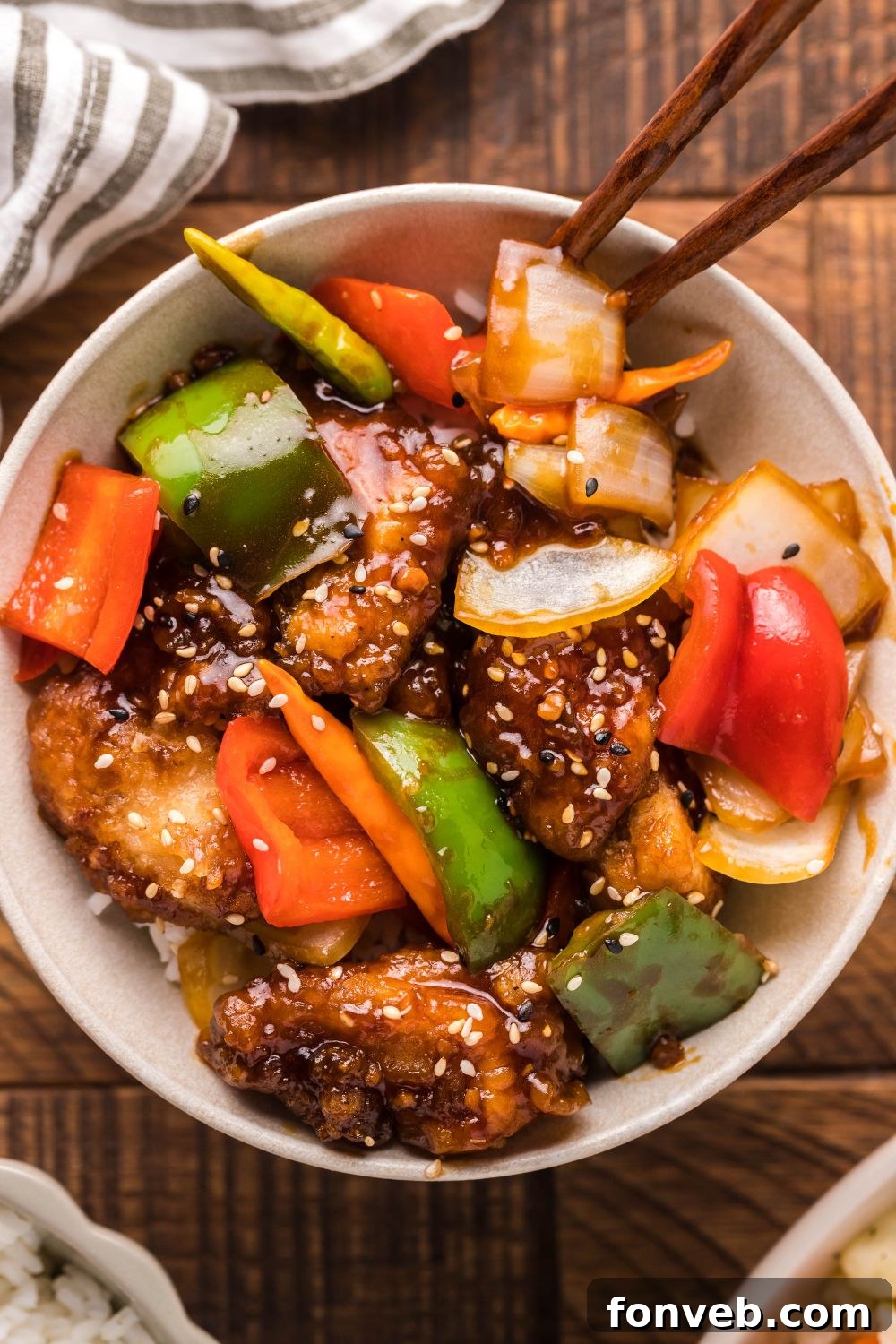 A vibrant bowl of General Tso Chicken, mixed with colorful veggies and generously topped with sesame seeds for garnish.