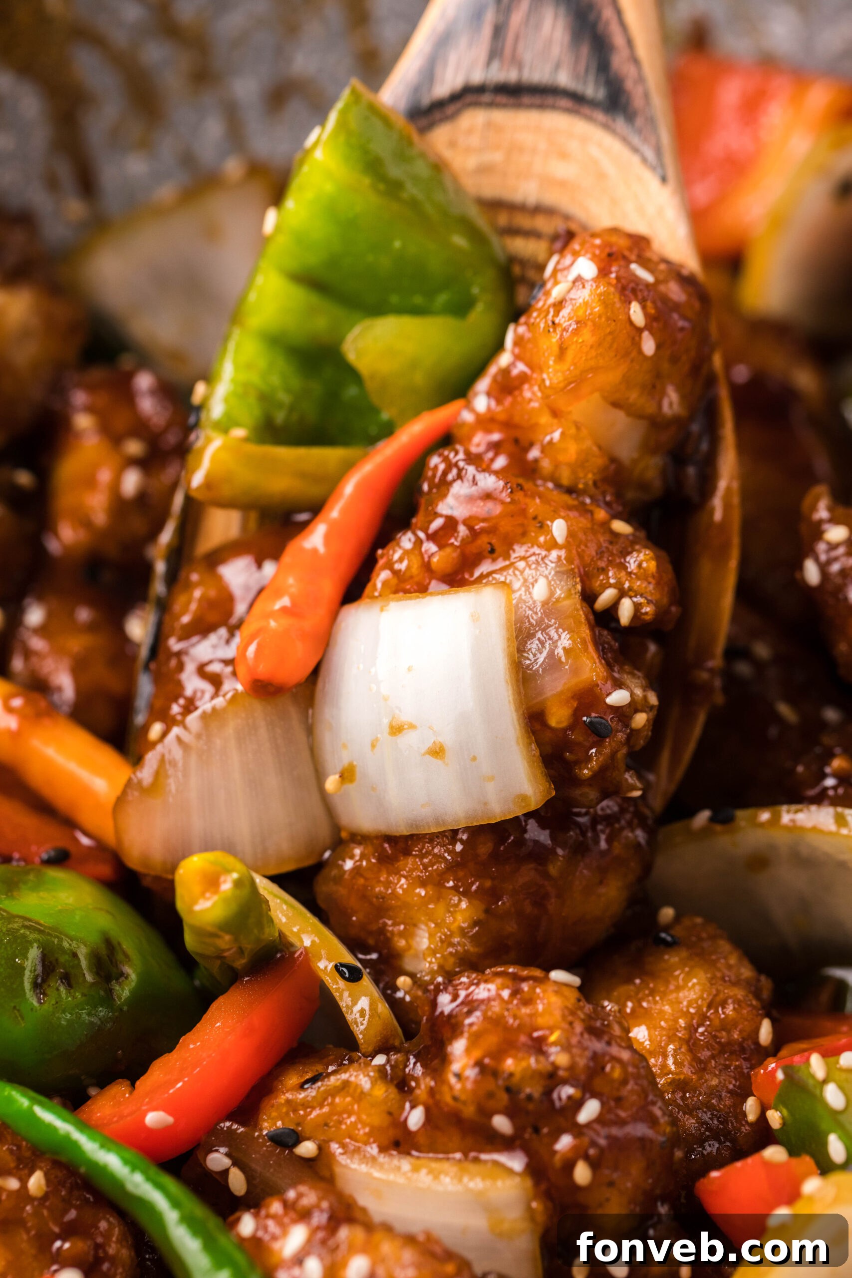Close-up shot of General Tso Chicken on a wooden spoon, showcasing the rich sauce and crispy coating.