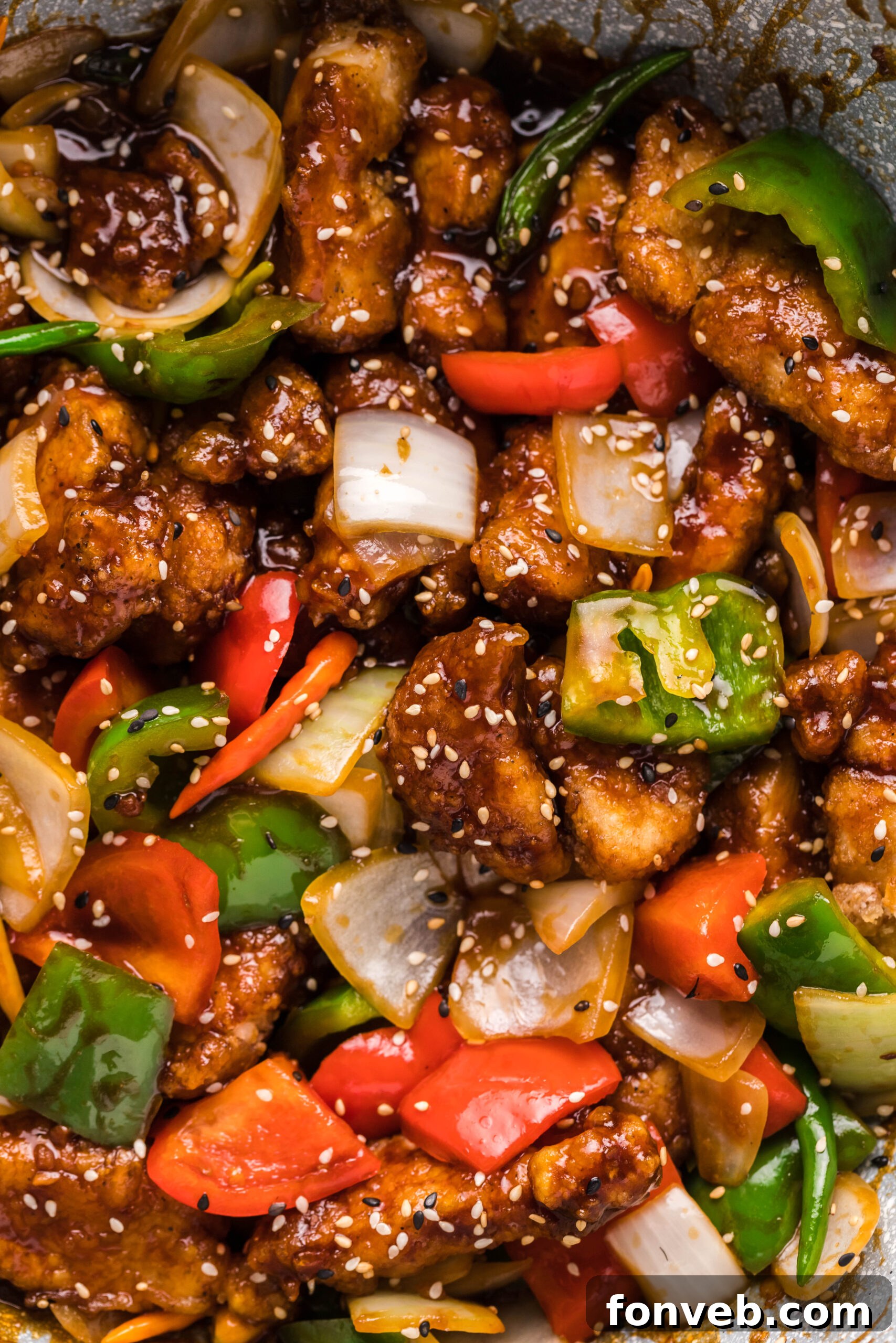 General Tso Chicken sizzling in a hot skillet, coating each piece in the glossy sauce.