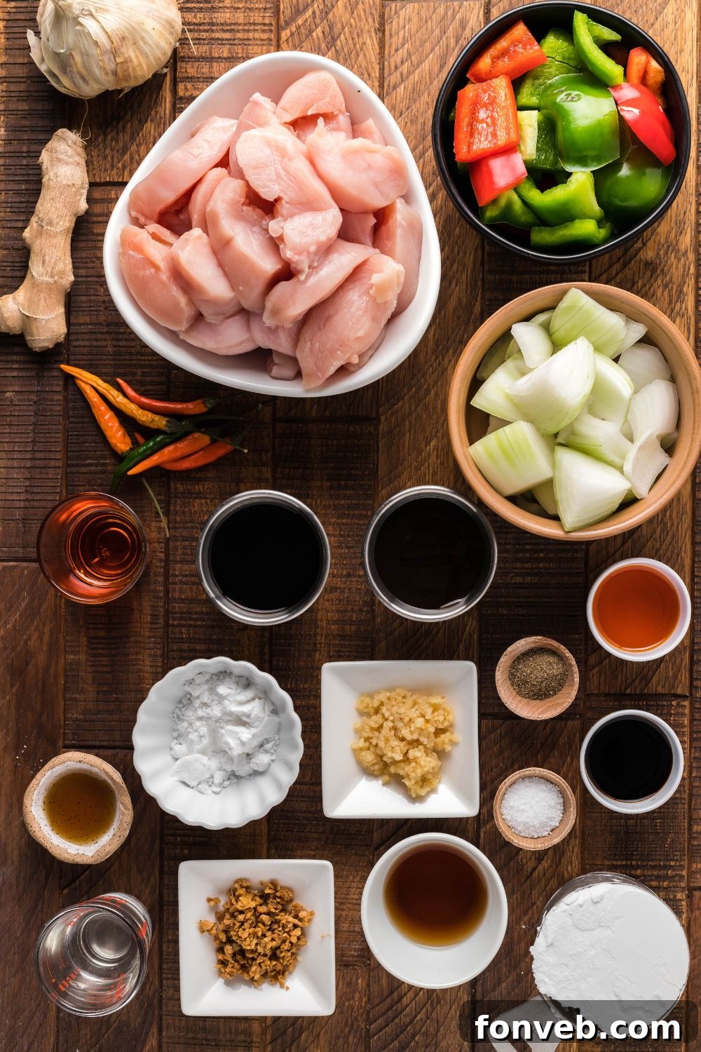 All the fresh ingredients for General Tso Chicken laid out in single-serve bowls on a wooden table, ready for preparation.