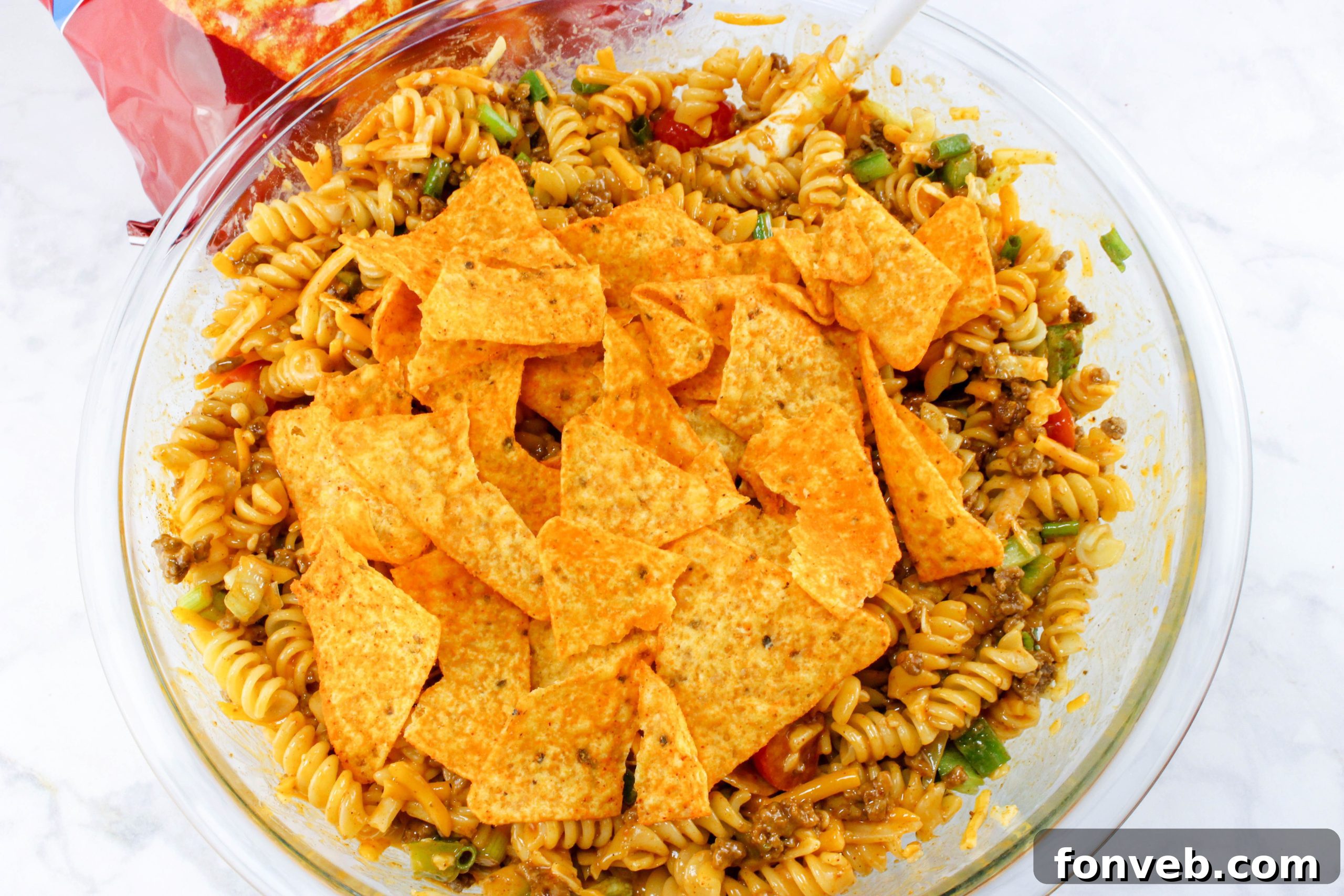Doritos Taco Pasta Salad garnished with sour cream and green onions.