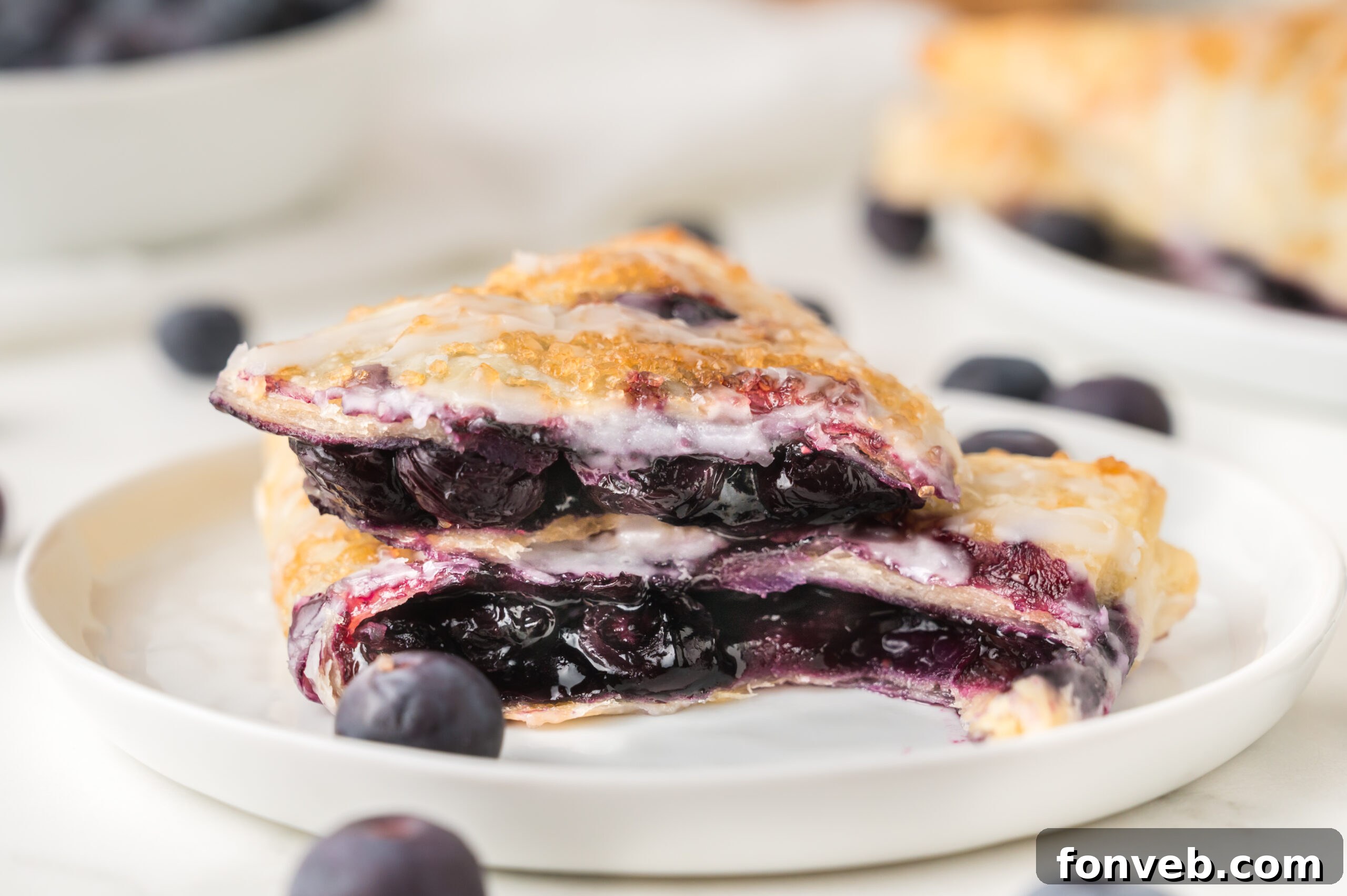 A beautifully composed shot of blueberry turnovers on a plate, surrounded by plump fresh blueberries, emphasizing their appealing texture and the vibrant fruit.