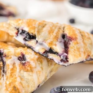 Blueberry Turnovers on plate with fresh blueberries around them on the plate