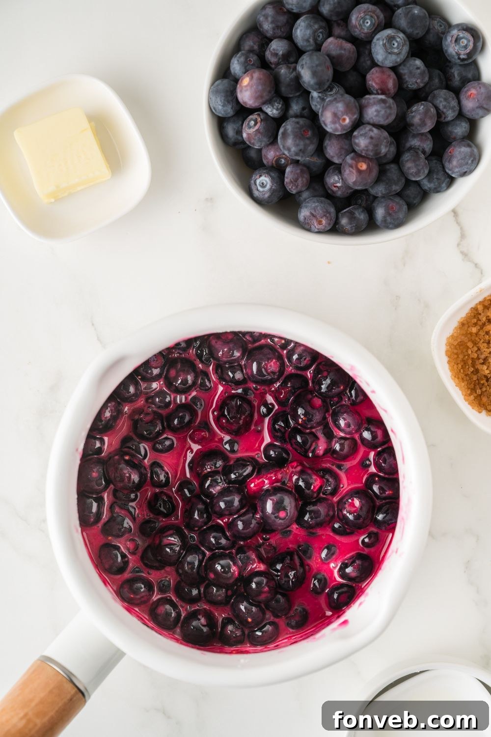 Blueberry turnover filling gently simmering in a saucepan on the stovetop, showing the process of thickening the fruit mixture.