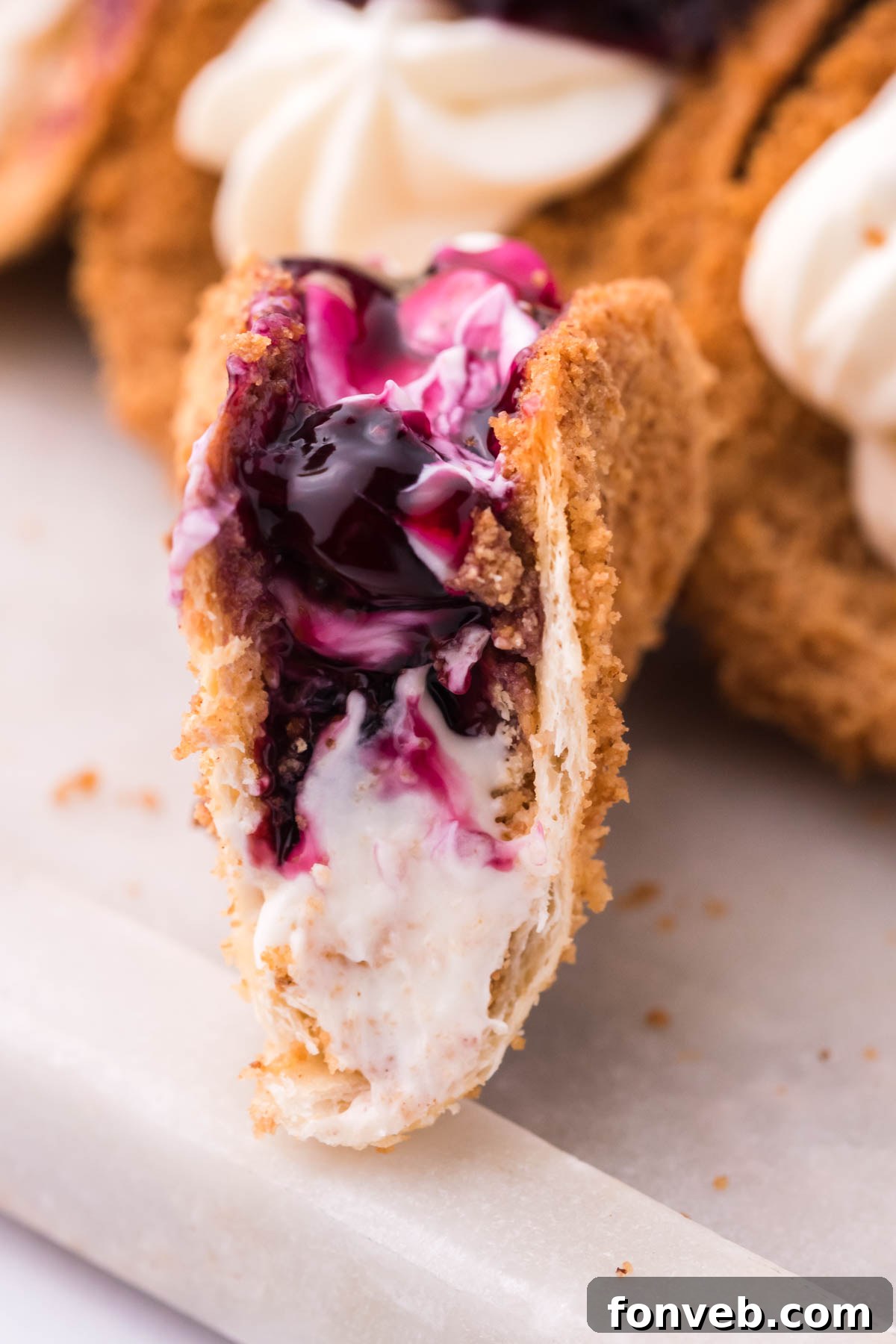 Blueberry Cheesecake Taco Twist 5 Close up shot of a bite removed from the cheesecake tacos showing the filling.