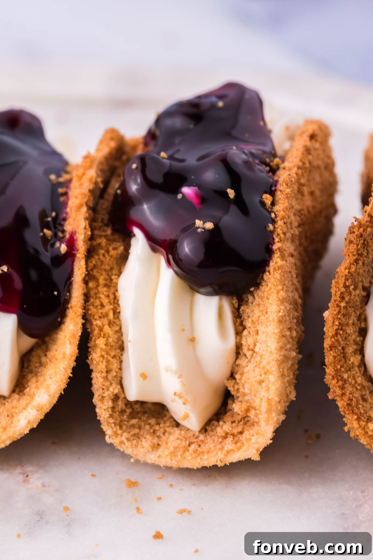 Blueberry Cheesecake Taco Twist 7 Photo of blueberry cheesecake tacos lined up on a marble serving platter.