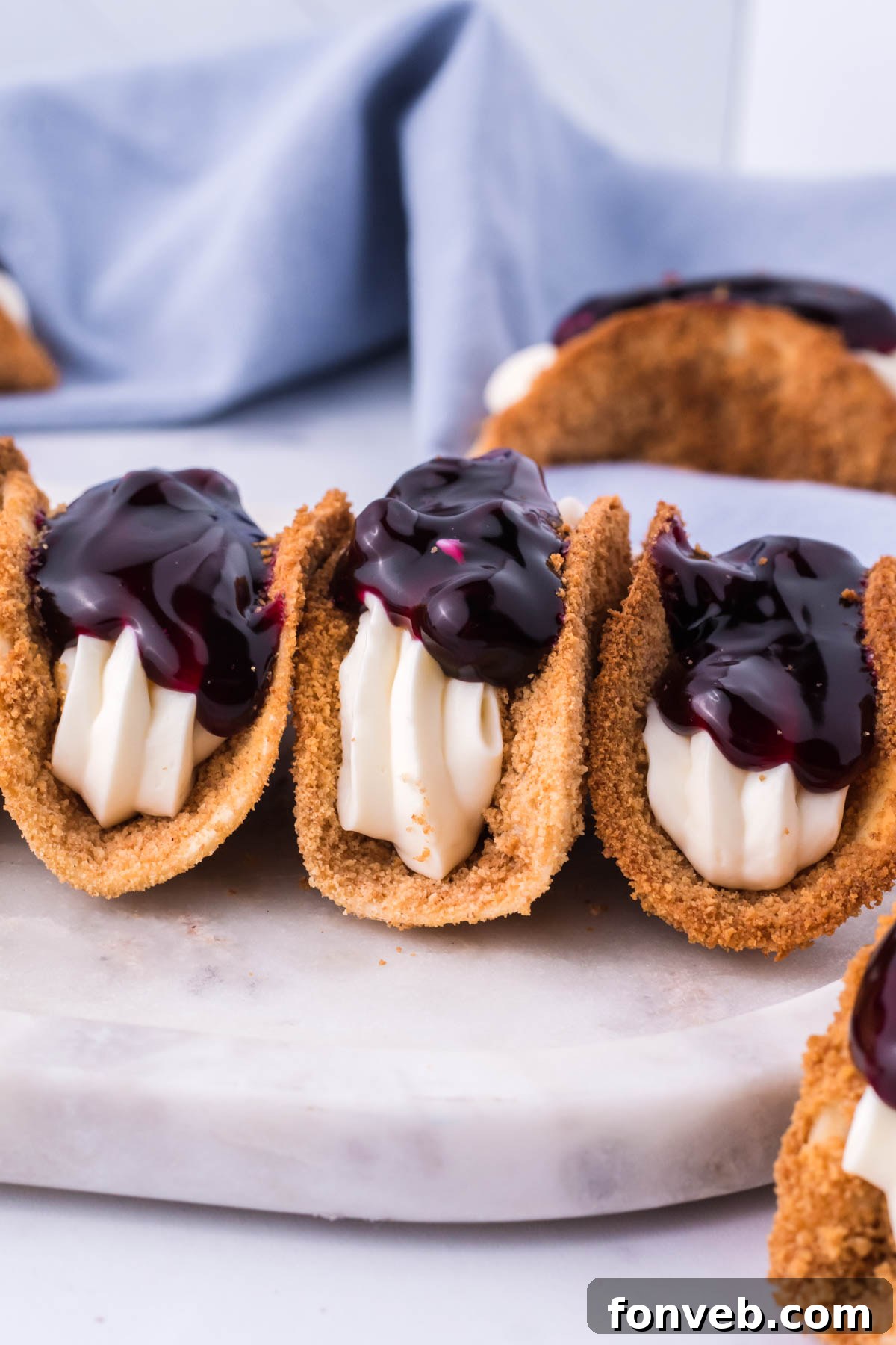Blueberry Cheesecake Taco Twist 8 Photo of blueberry cheesecake tacos lined up on a marble serving platter.