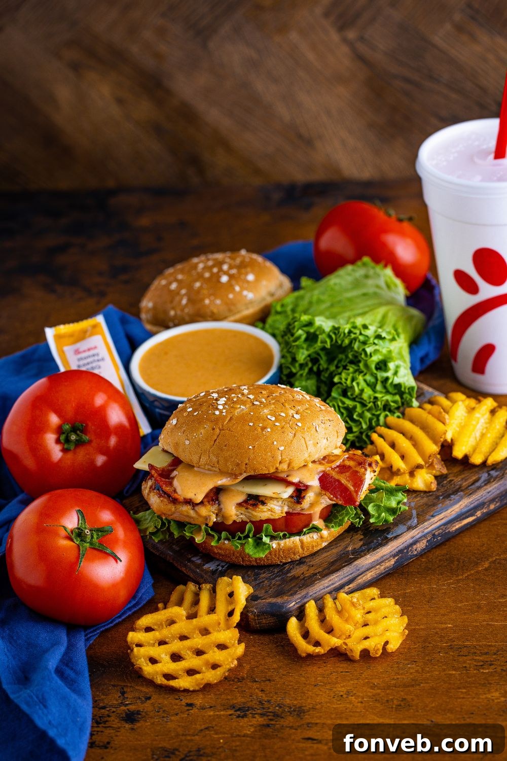 A complete meal setting with a Chick-fil-A style grilled chicken sandwich, drink, fries, and sauce on a table, ready to be enjoyed.
