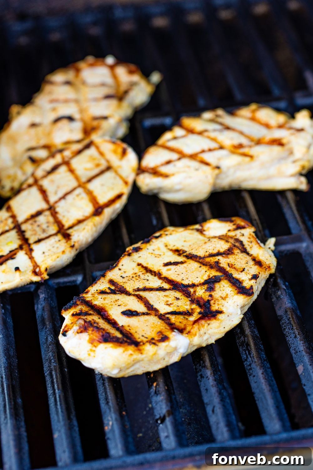 Juicy chicken searing on a hot grill, creating perfect char marks for a grilled chicken sandwich.