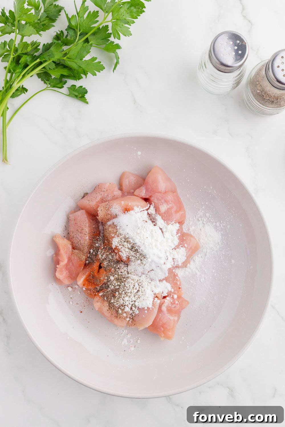 diced chicken on plate with seasonings on top of the chicken