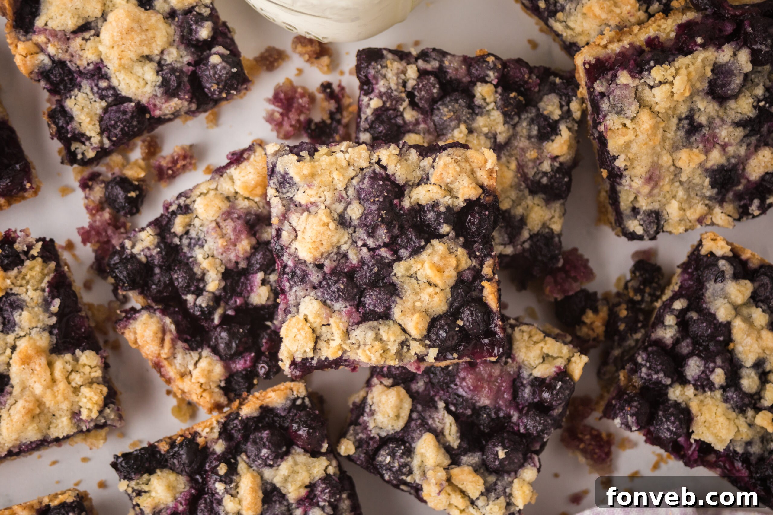 blueberry crumble bars stacked on a white table 