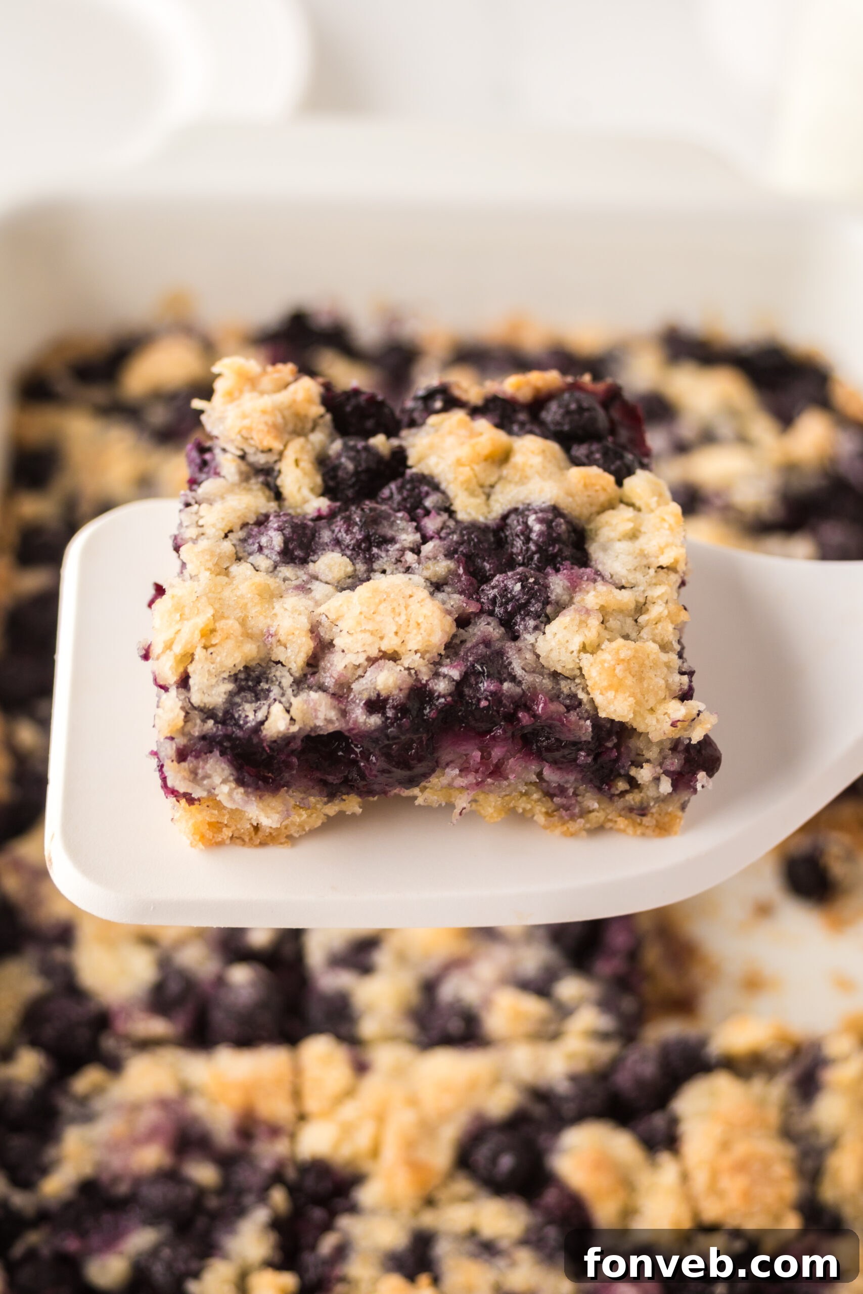 blueberry crumble bar being lifted up by a white spatula