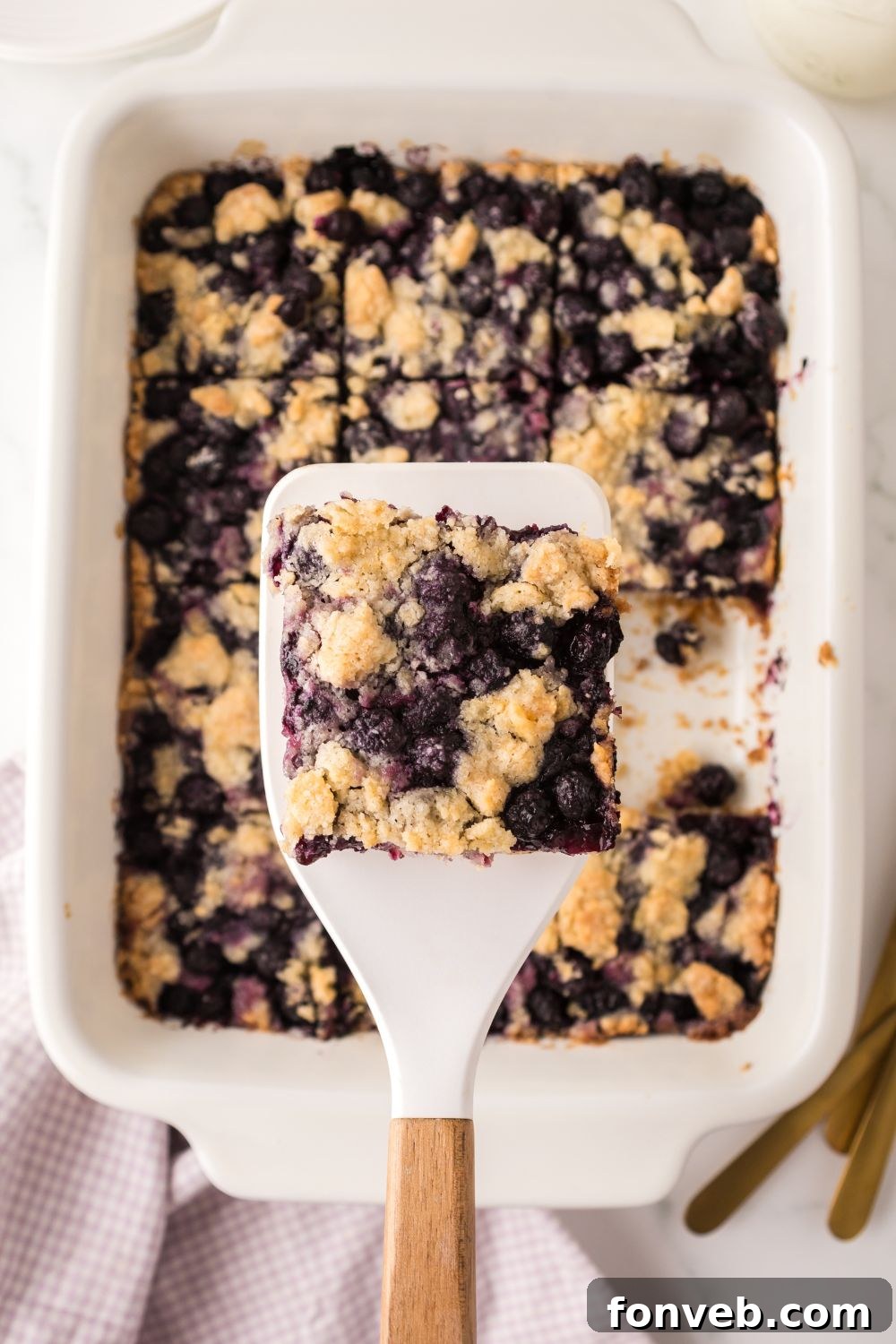 Blueberry Crumb Bar on a spatula above the casserole dish 