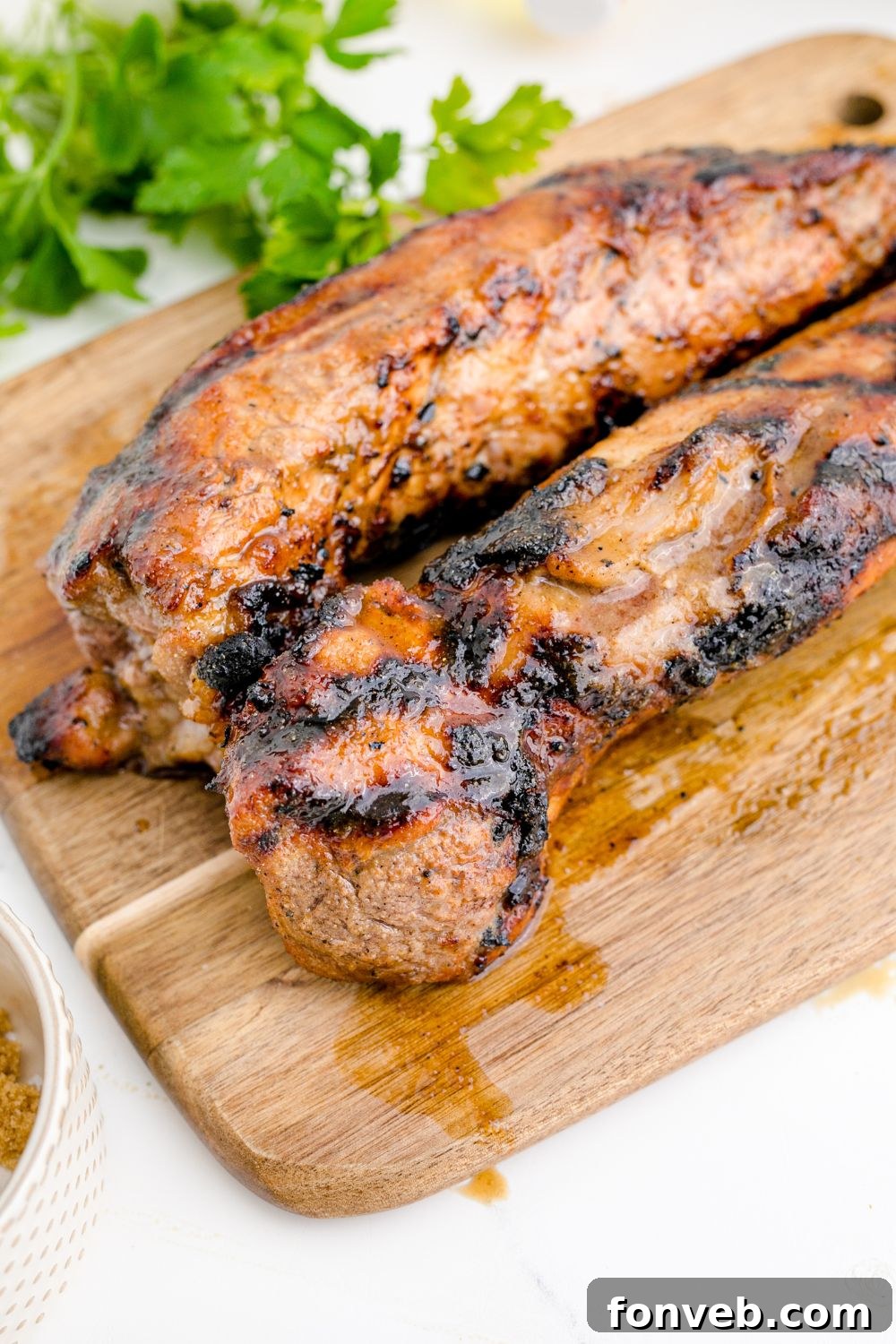 Grilled Pork Tenderloin that is cooked sitting on a wooden cutting board 