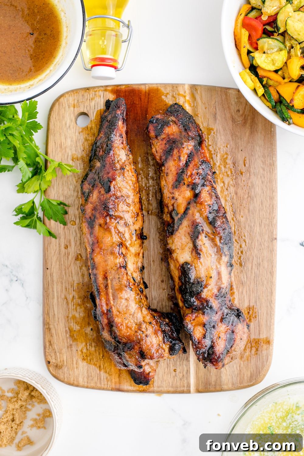 Grilled Pork Tenderloins on a cutting board with parsley around it on table