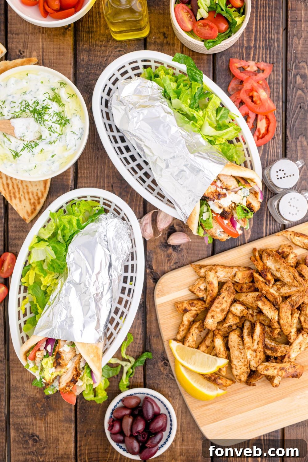 overhead look of chicken gyros in baskets with fresh veggies around it on table 