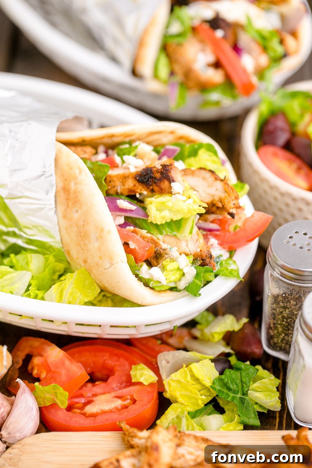 plate with chicken gyros with fresh veggies on top in a pita 