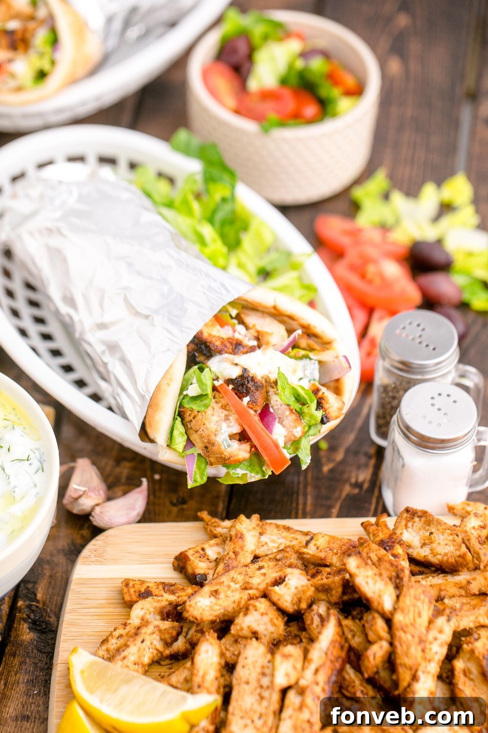 Chicken Gyro wrap in a basket with a cutting board with chicken in front of it 