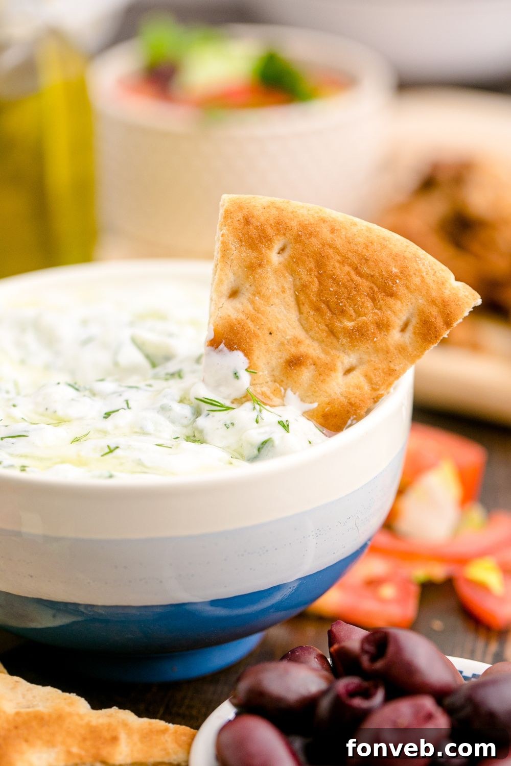 Traditional Greek tzatziki in a bowl with a pita wedge in the dip