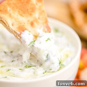 Tzatziki Sauce in a bowl with a pita dipped in sauce