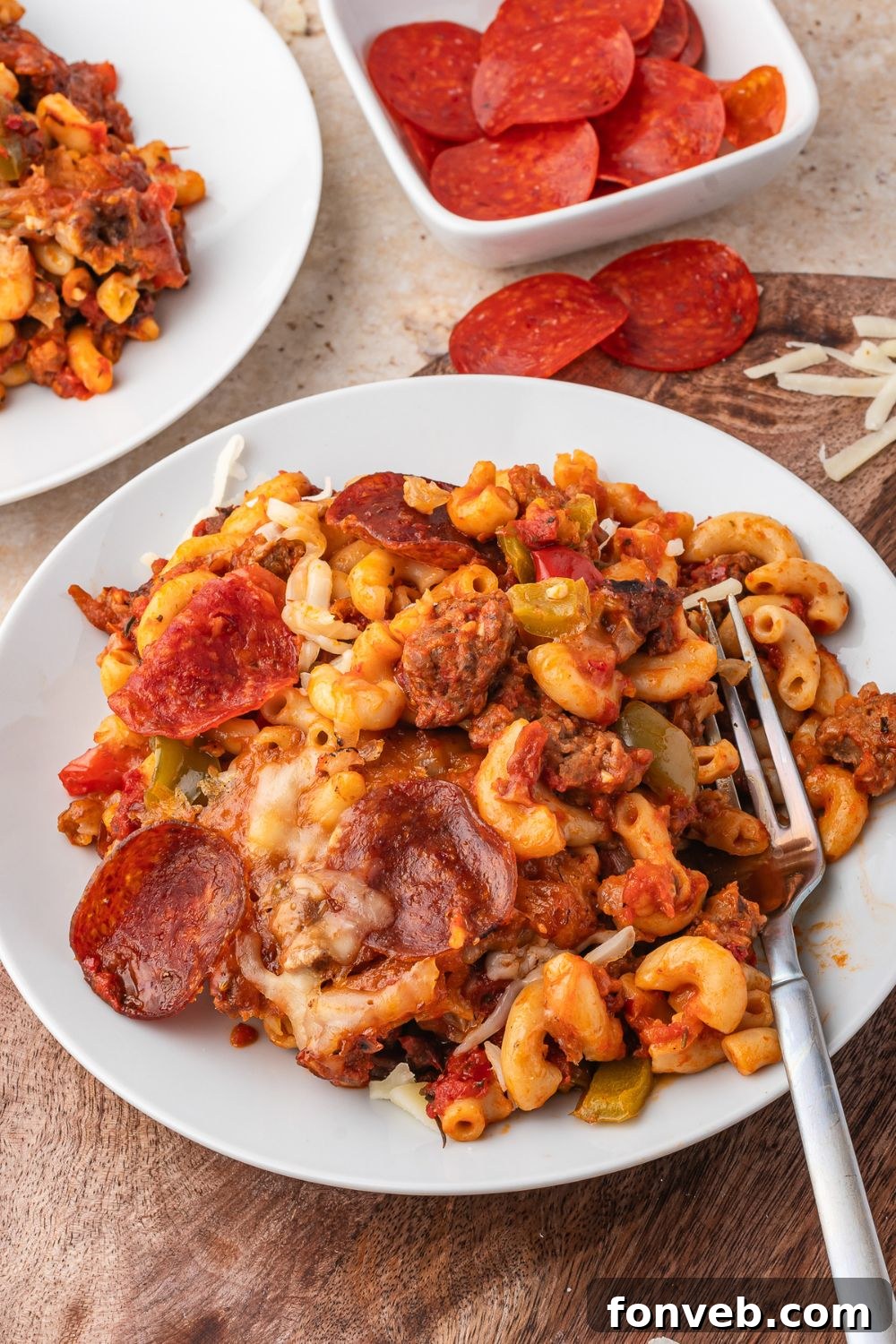 plates with cheesy pepperoni pizza pasta on each plate with forks