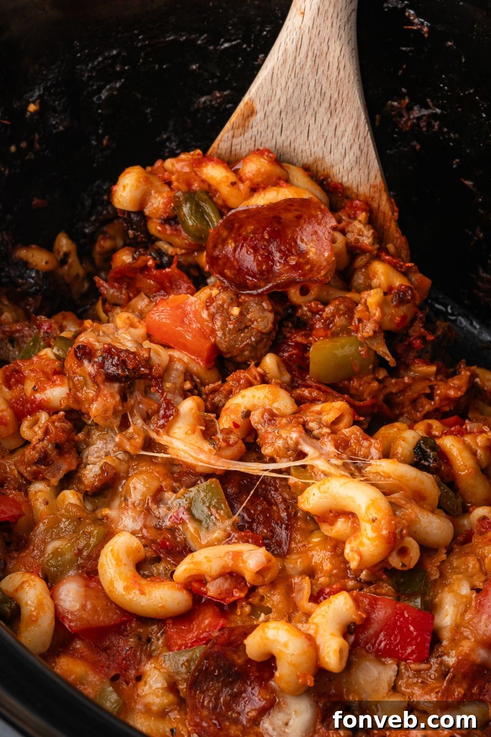 Slow Cooker Pizza Casserole with a spoon being scooped out of crock pot