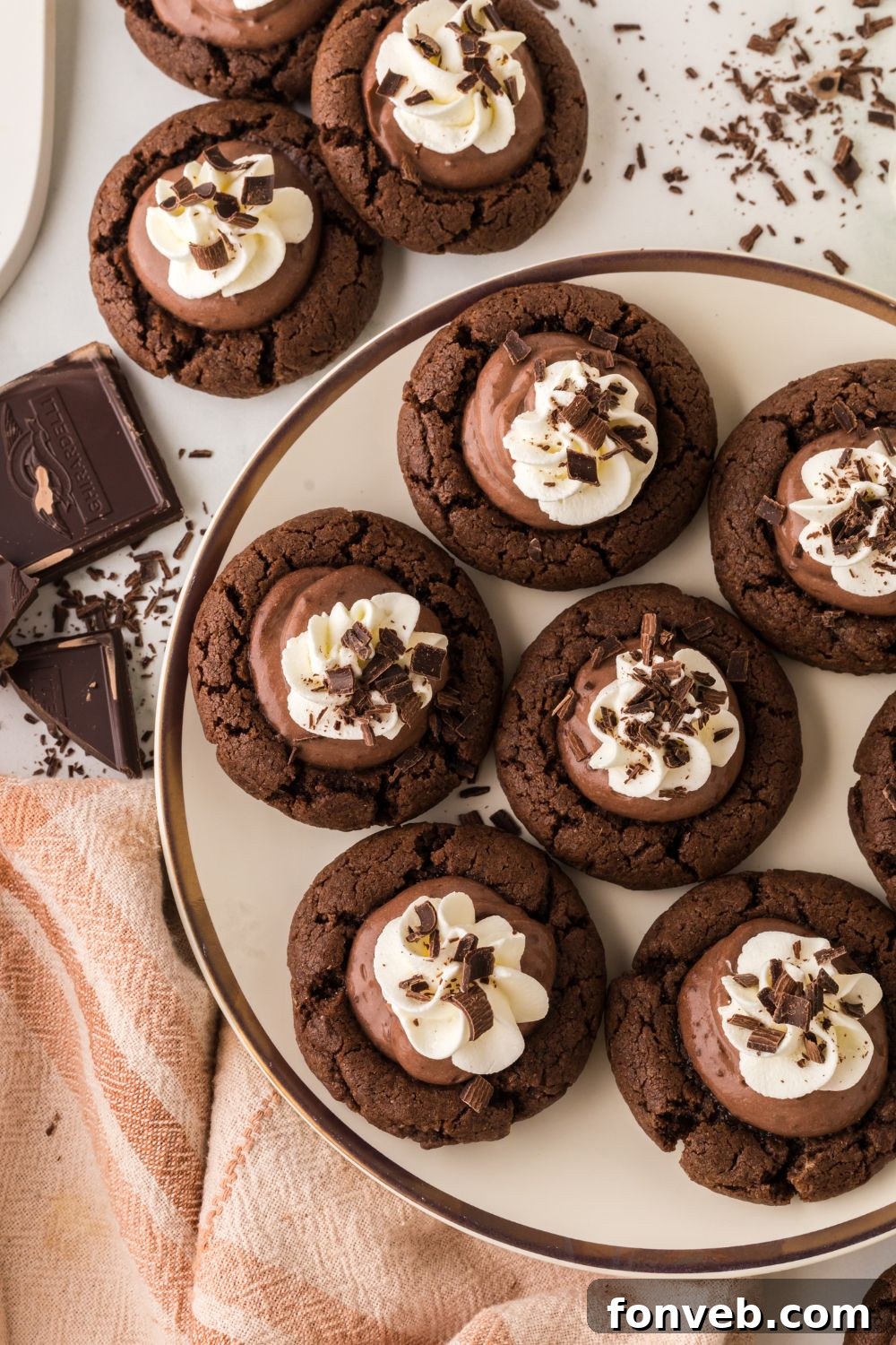 Chocolate Pie Cookies arranged artfully on a plate, surrounded by other enticing cookies on a table, all adorned with delicate chocolate shavings.