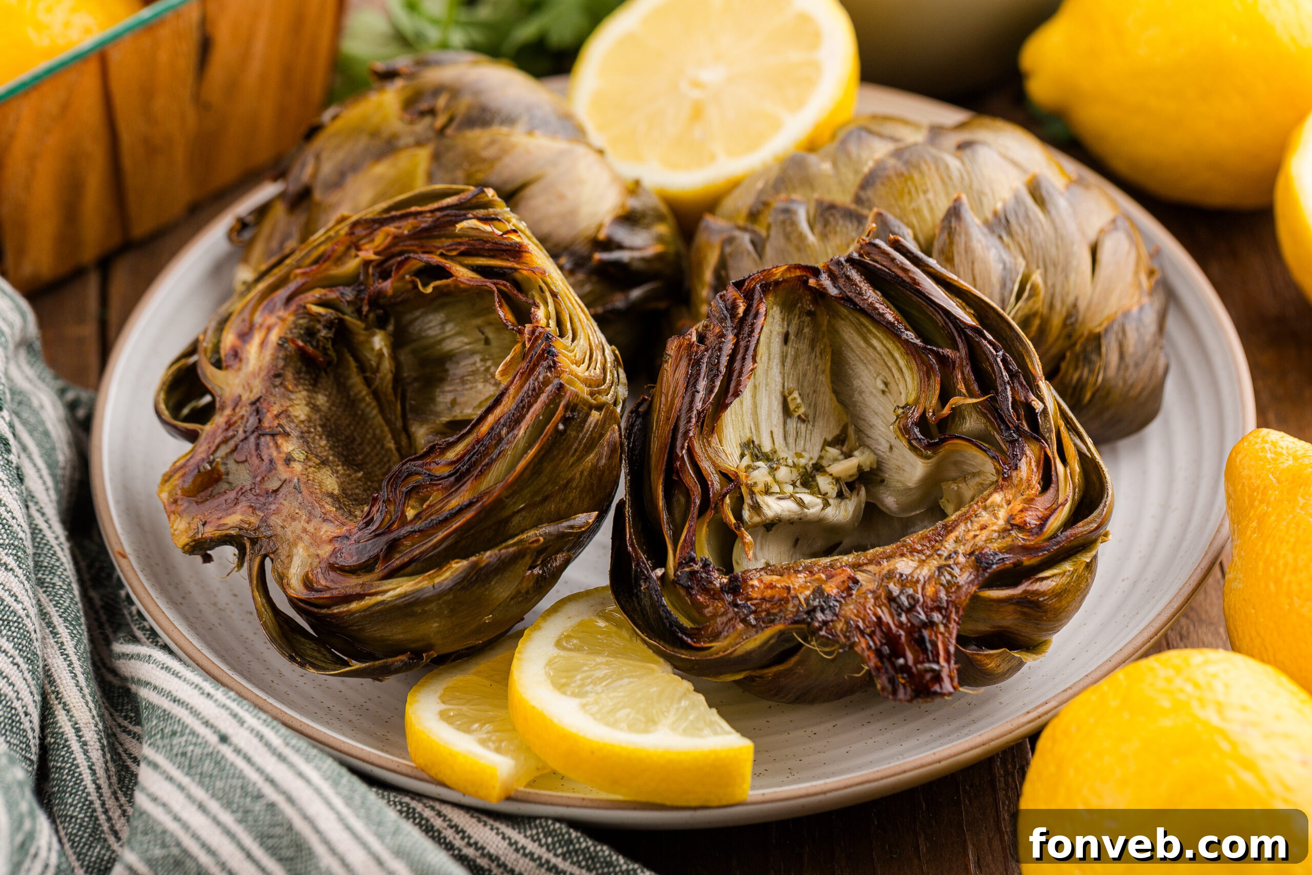 4 roasted artichokes on a plate with sliced lemons
