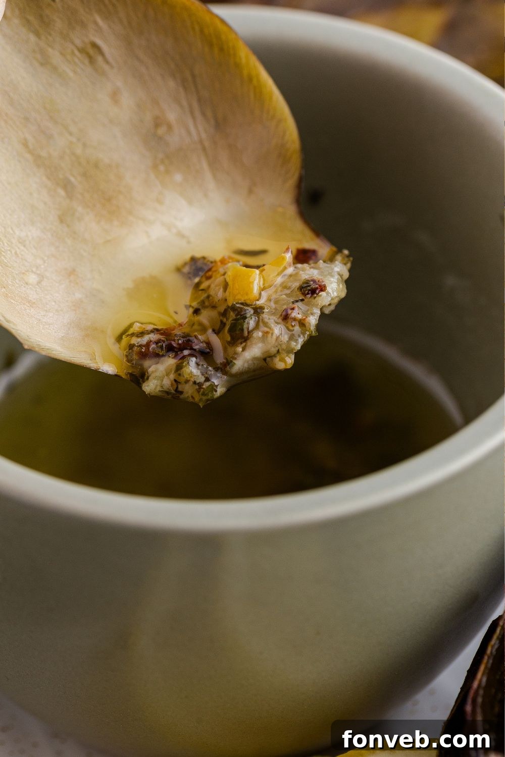 artichoke dipped in oil mixture from a bowl