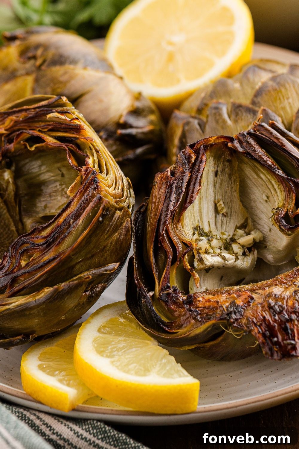 Oven Roasted Artichokes sitting on plate with sliced lemons