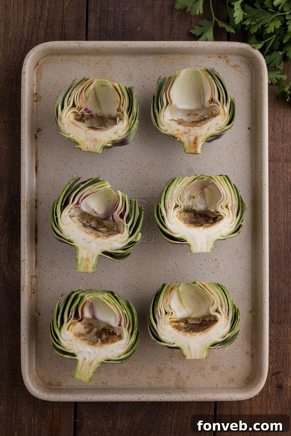 sliced artichokes sitting face up on a baking tray