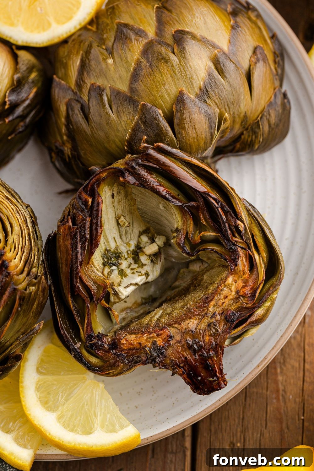 Oven Roasted Artichokes on table with lemon wedges on the side