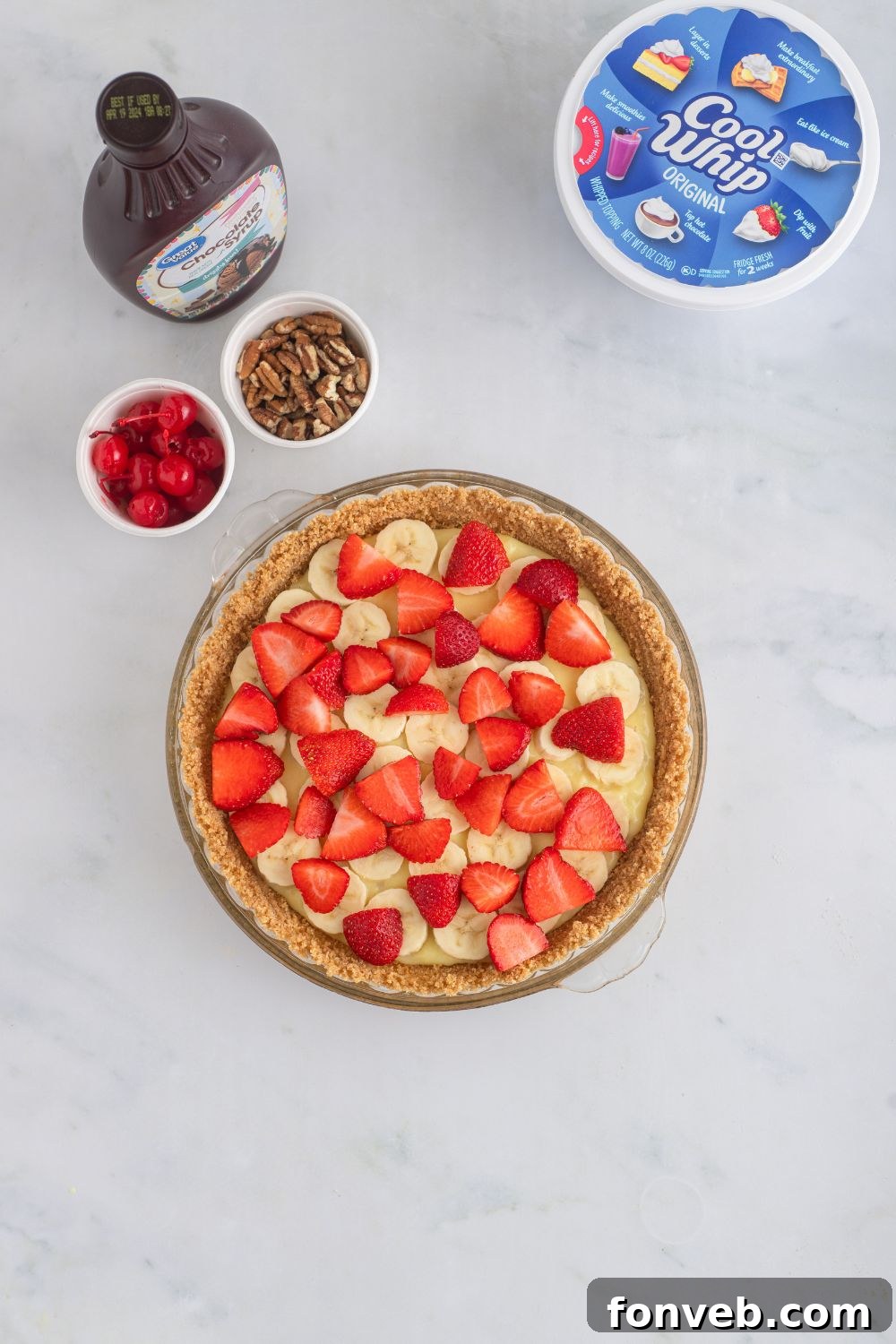 Fresh strawberry slices carefully placed on top of the banana layer in the pudding-filled pie crust.