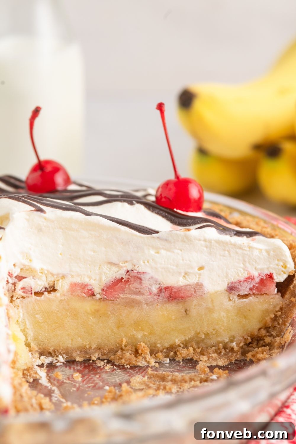 A whole No Bake Banana Split Pie with a single piece removed, clearly showcasing the beautiful, distinct layers within.