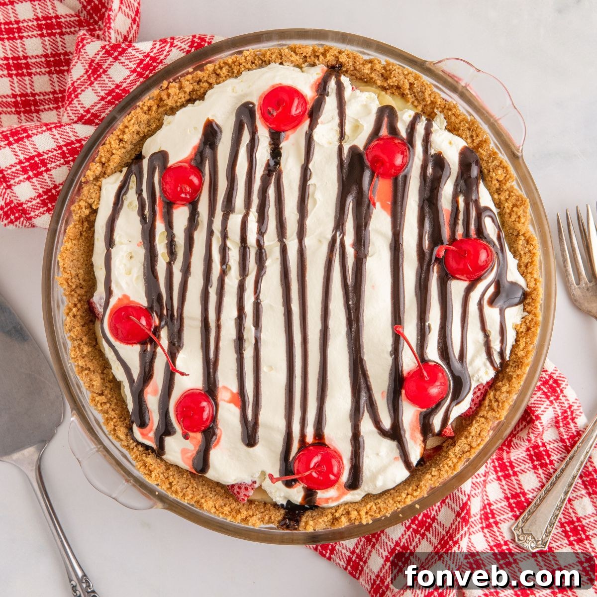 A whole No Bake Banana Split Pie artfully arranged on a table with a decorative napkin beneath it, ready to be served.