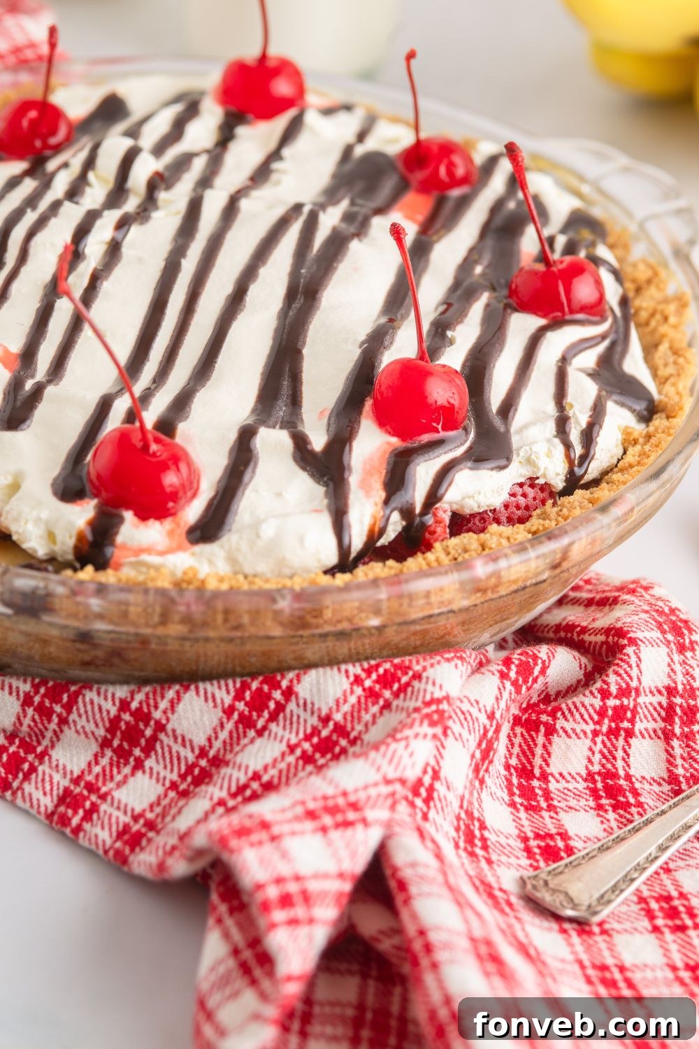 A captivating side view of a No Bake Banana Split Pie on a table, resting on a charming checked towel.