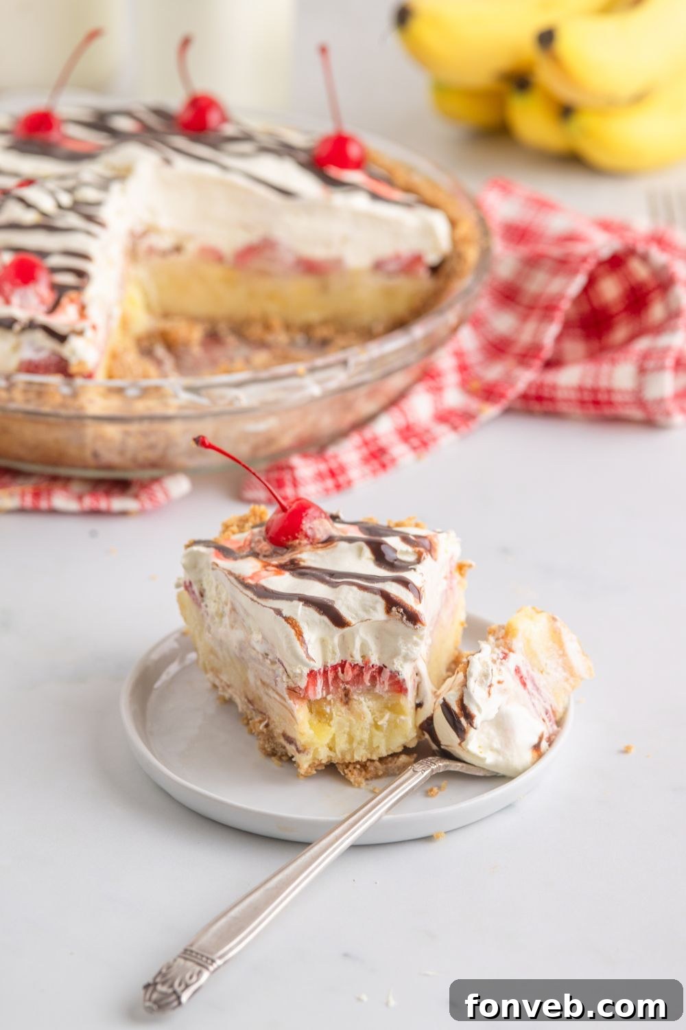 A slice of No Bake Banana Split Pie on a plate, with a bite taken, showcasing its distinct layers of crust, fruit, and creamy filling.