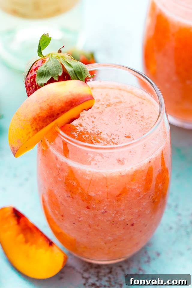 Refreshing Strawberry Peach Wine Slushies in elegant glasses, garnished with fresh fruit