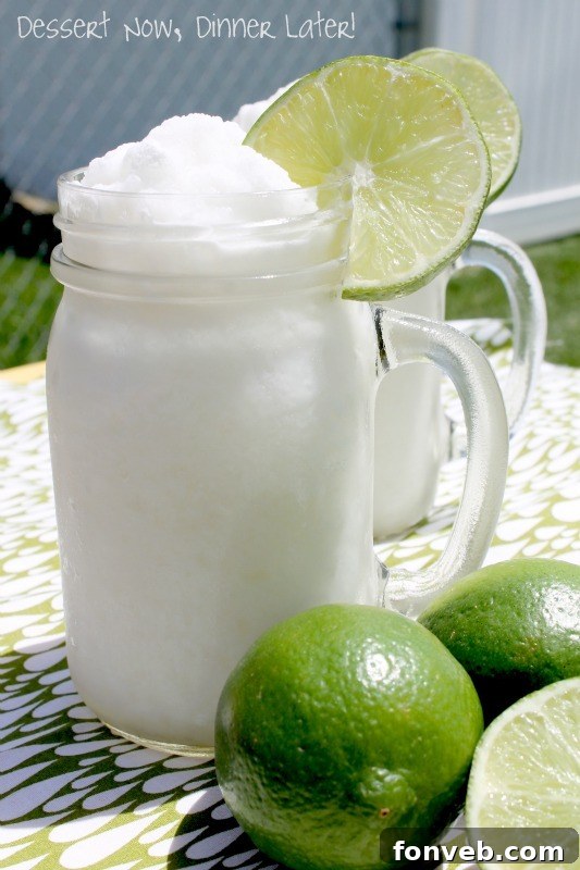 Glass of frosty Frozen Coconut Limeade, garnished with a fresh lime wedge