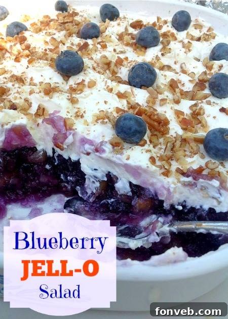 Blueberry JELL-O Salad in a clear glass dish, garnished with whipped topping and blueberries