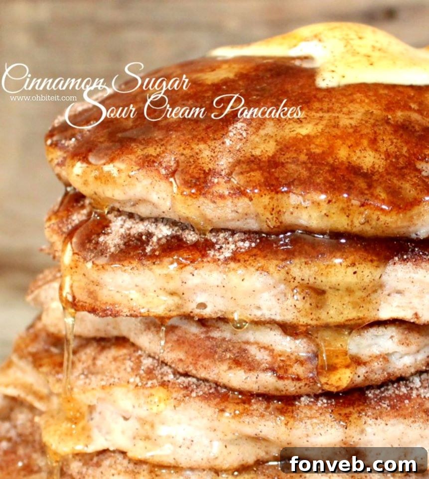 Stack of fluffy Cinnamon Sugar Sour Cream Pancakes drizzled with syrup
