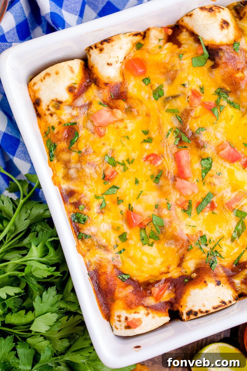close up view of enchiladas in a casserole dish on table with cilantro to the side 
