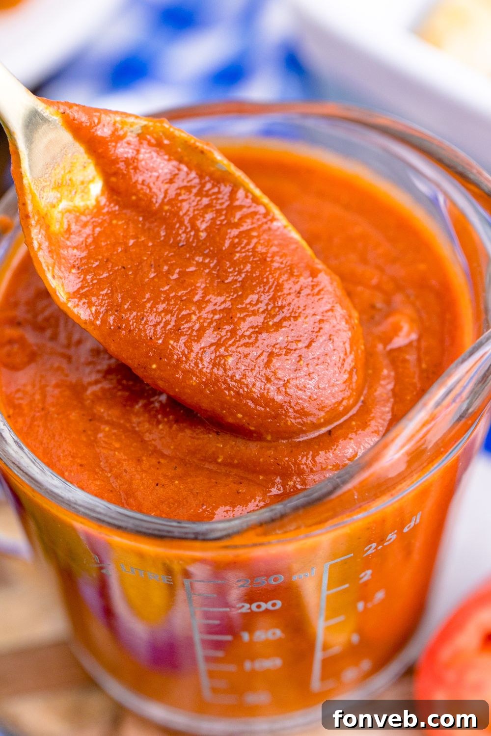 spoon with Homemade Enchilada Sauce on it above container with more sauce 