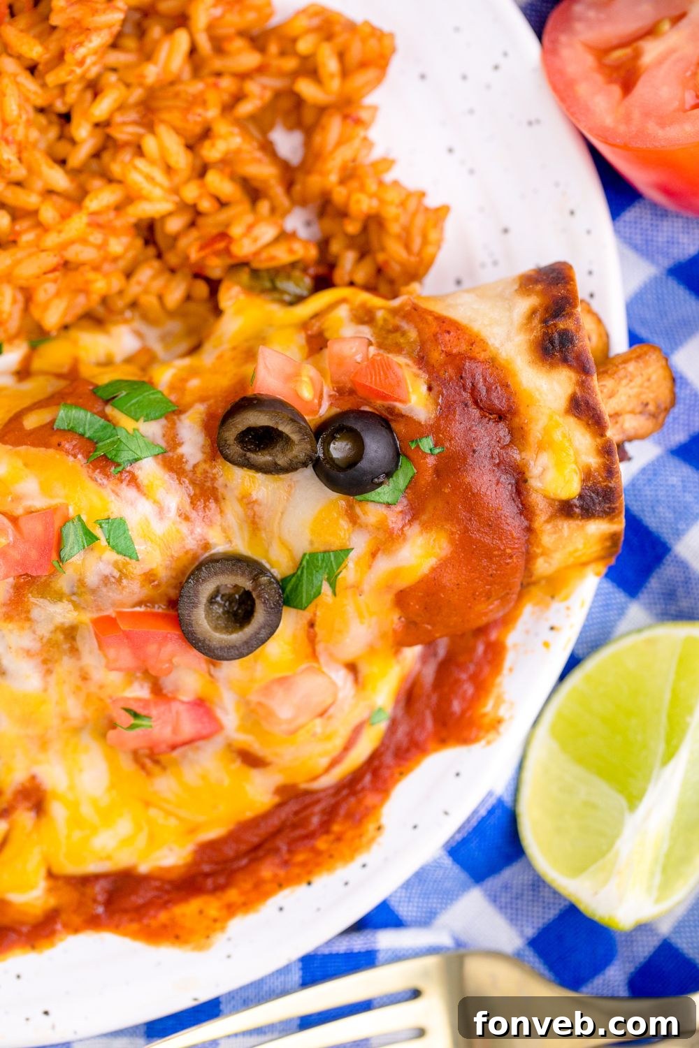 close up of enchilada topped with cheese and a side of rice to the side on plate 