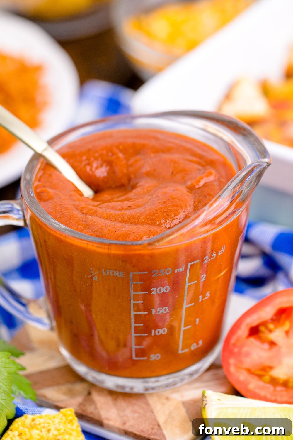 Homemade Enchilada Sauce in a measuring cup with spoon inside container 