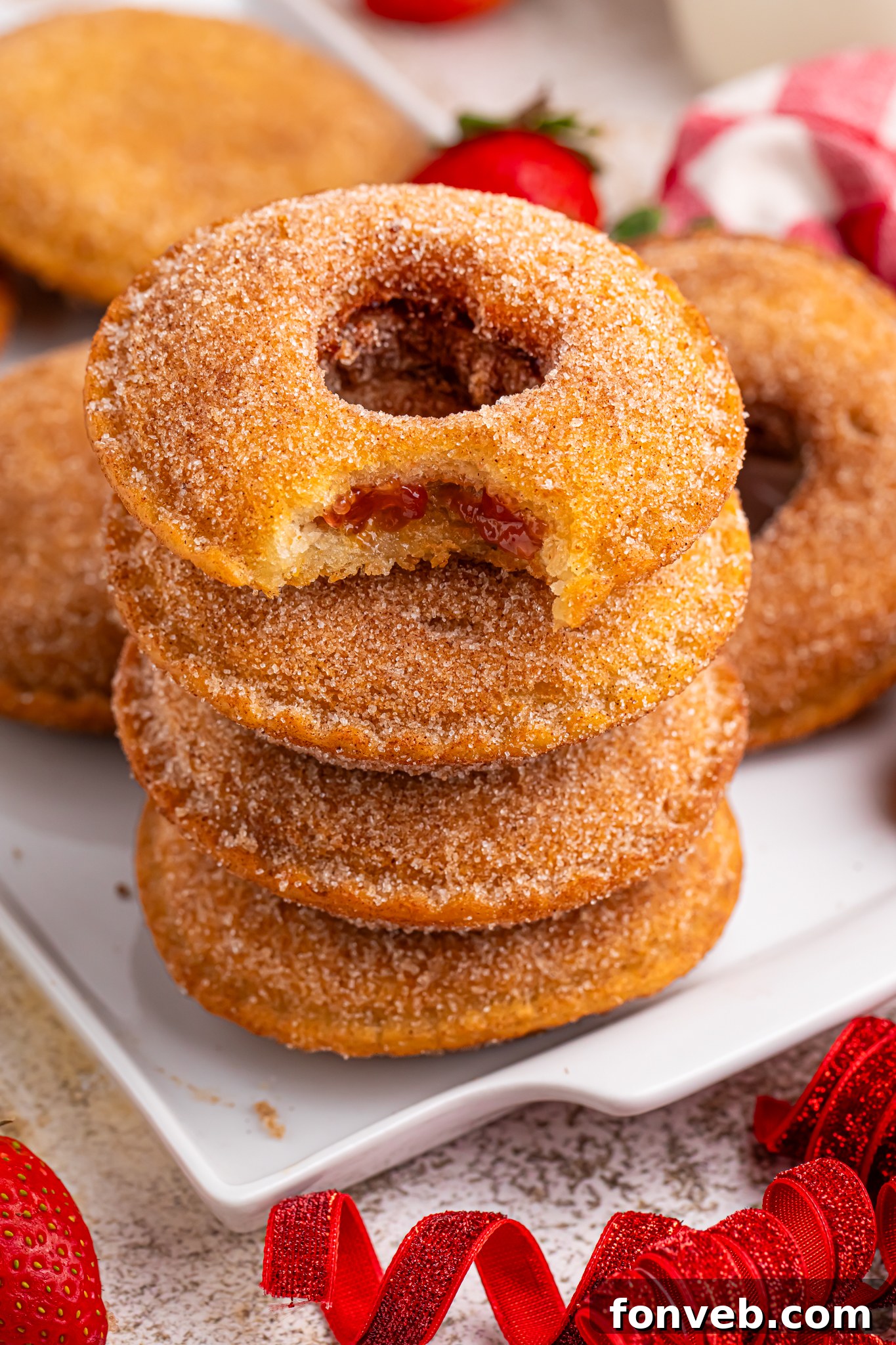 plate with Fried Strawberry Uncrustables that have been fried and rolled in sugar on plate with strawberries in front of plate 