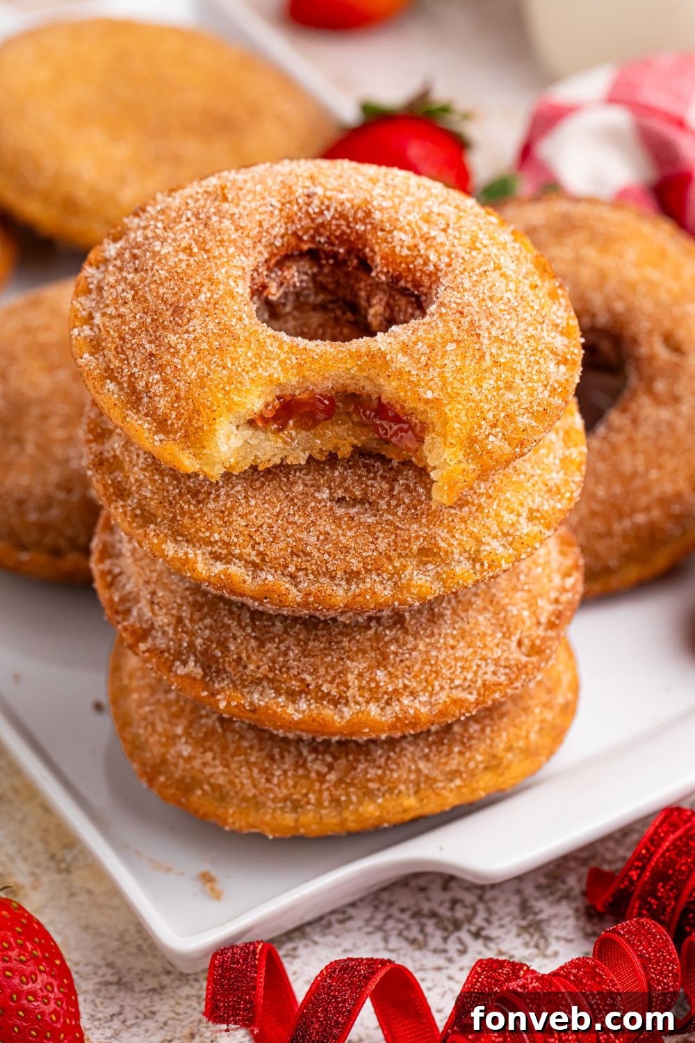 stack of Fried Strawberry Uncrustables that have been fried on table with heart shapes cut out in each of the centers stacked on table 