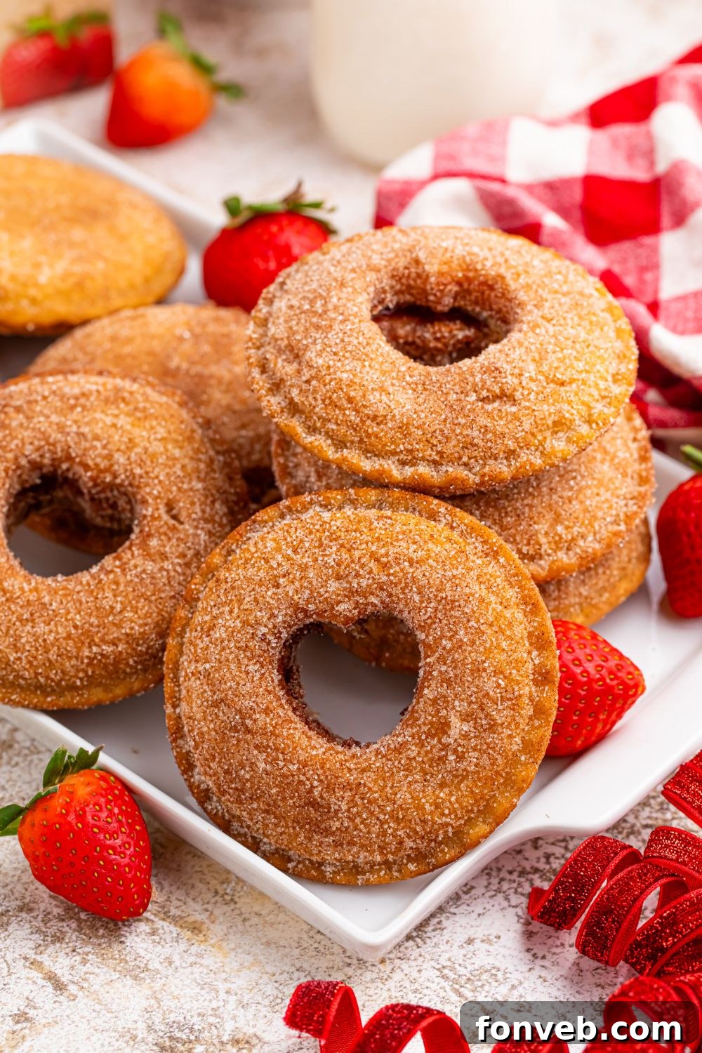 Fried Strawberry Uncrustables with hearts cut out in centers on a tray, and strawberries and other red items around table 