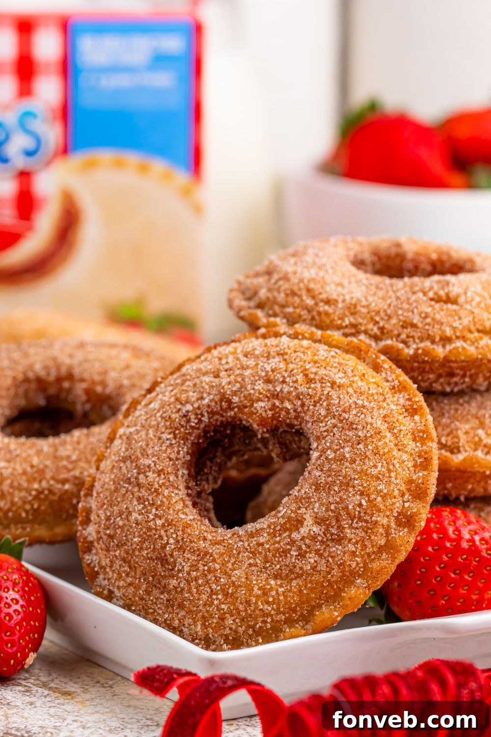 close up of Fried Strawberry Uncrustables on table with hearts cut out in center and box of sandwiches in background 